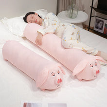 Person lying on a bed with a pink pig-shaped body pillow and headrest.