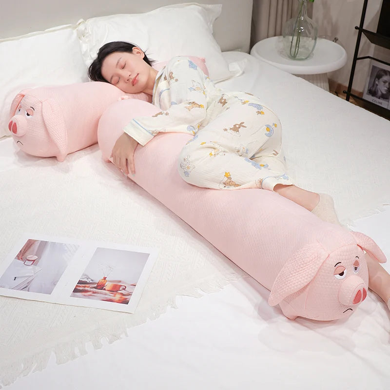 Person lying on a bed with a pink pig-shaped body pillow