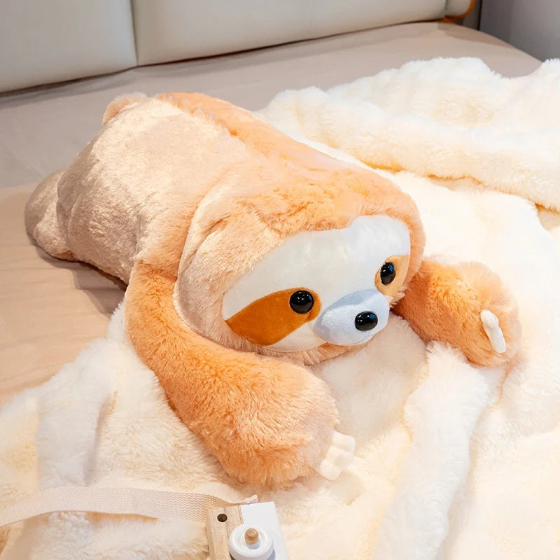 Plush toy sloth lying on a bed with a white blanket