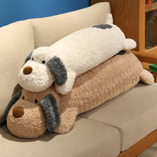 Large plushie toy dog pillow on a beige couch against a blue wall.