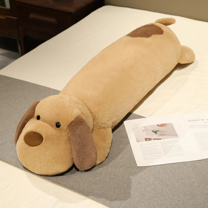 Dog-shaped body pillow plushie on a bed next to a magazine
