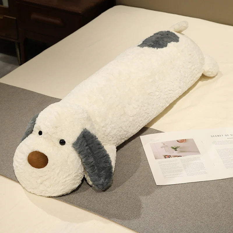 Dog-shaped plushie body pillow on a bed next to a magazine