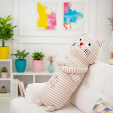 Striped cat-shaped plushie pillow on a couch with colorful wall art and plants in the background