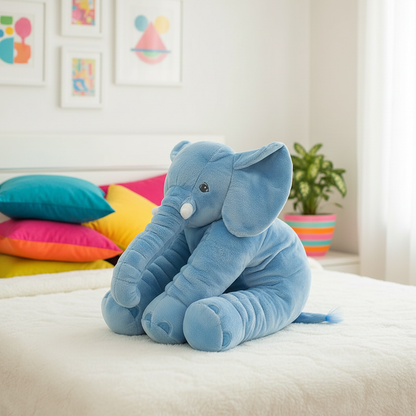 Blue elephant plush toy on a bed with colorful pillows and a plant in the background