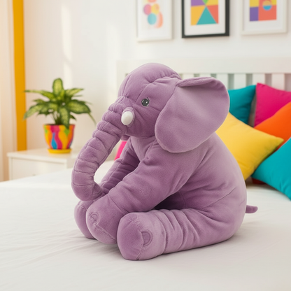 Purple elephant plush toy on a bed with colorful pillows and a plant in the background
