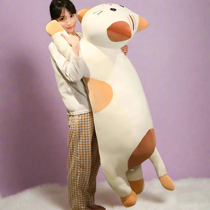 Person holding a large plush cat stuffed animal in a bedroom setting