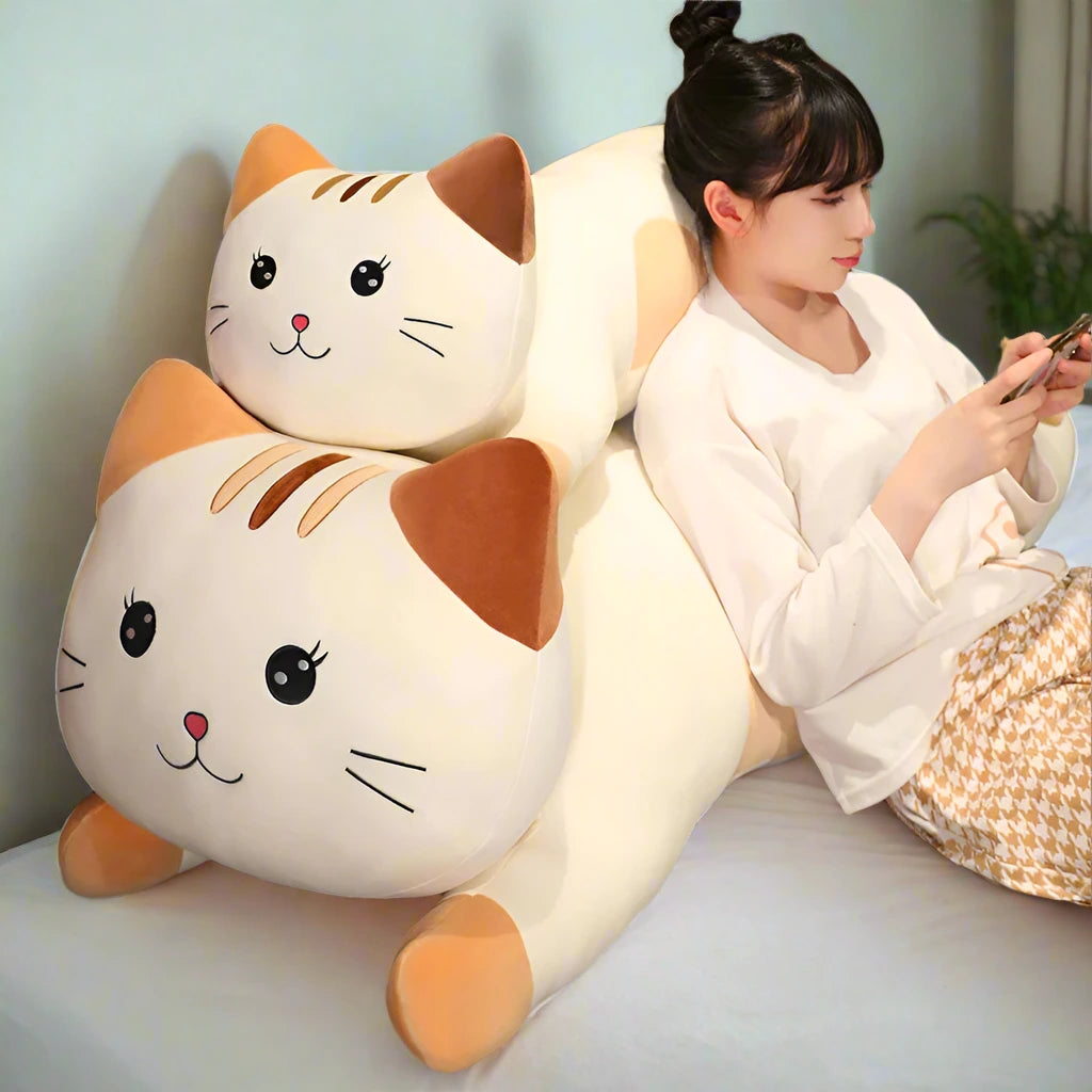 Woman sitting on a large cat-shaped body pillow in a cozy room.