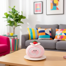 Pink plush toy with a strawberry on a wooden table in a living room.