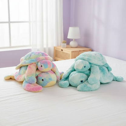 Two plush turtle toys, one multicolored and one blue, on a bed with a light purple wall and window in the background.