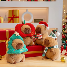 Four capybara plushies wearing Christmas hats and outfits on a festive background with presents and decorations.