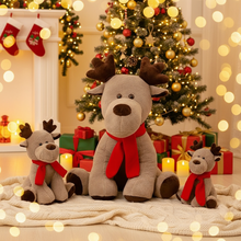 Decorative reindeer plush toys with red scarves in a festive setting with a Christmas tree and presents.