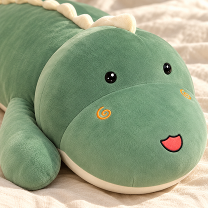 Close view of the Green dinosaur plush pillow's open eyes, spiral cheeks, smiling snout, and soft fabric.