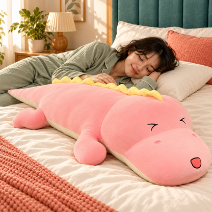Woman resting beside the full-length Pink dinosaur plush body pillow on an ivory bed.