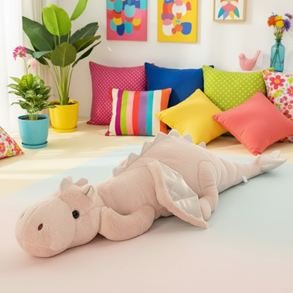 Long plush toy dragon on a bed with colorful pillows and plants in the background