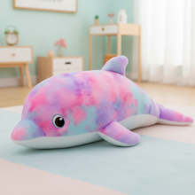 Colorful dolphin plush toy on a bed in a room with light green walls and wooden furniture.