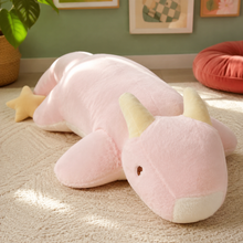 Close view of the blush pink Starry Snooze dragon plushie body pillow with golden horns, a small wing, and star tail