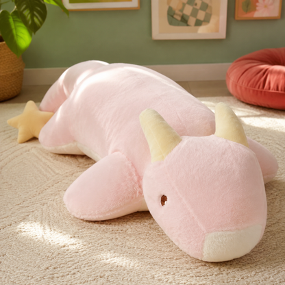 Close view of the blush pink Starry Snooze dragon plushie body pillow with golden horns, a small wing, and star tail