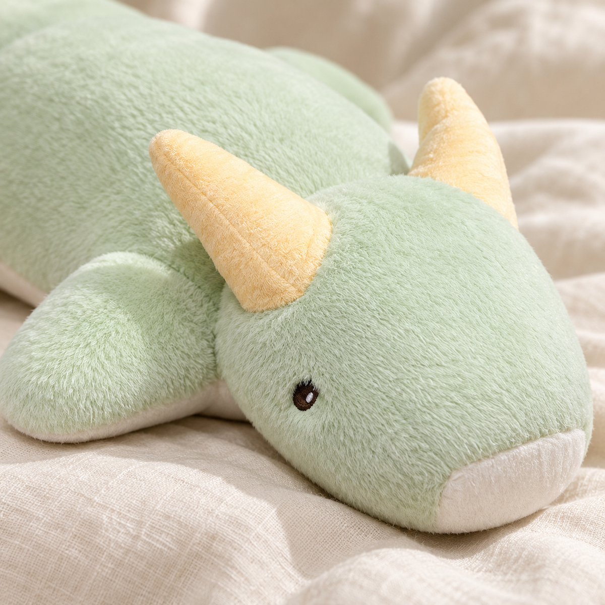 Close view of the Mint Green Starry Snooze dragon's sleepy face, cream muzzle, pale yellow horns, and plush fabric