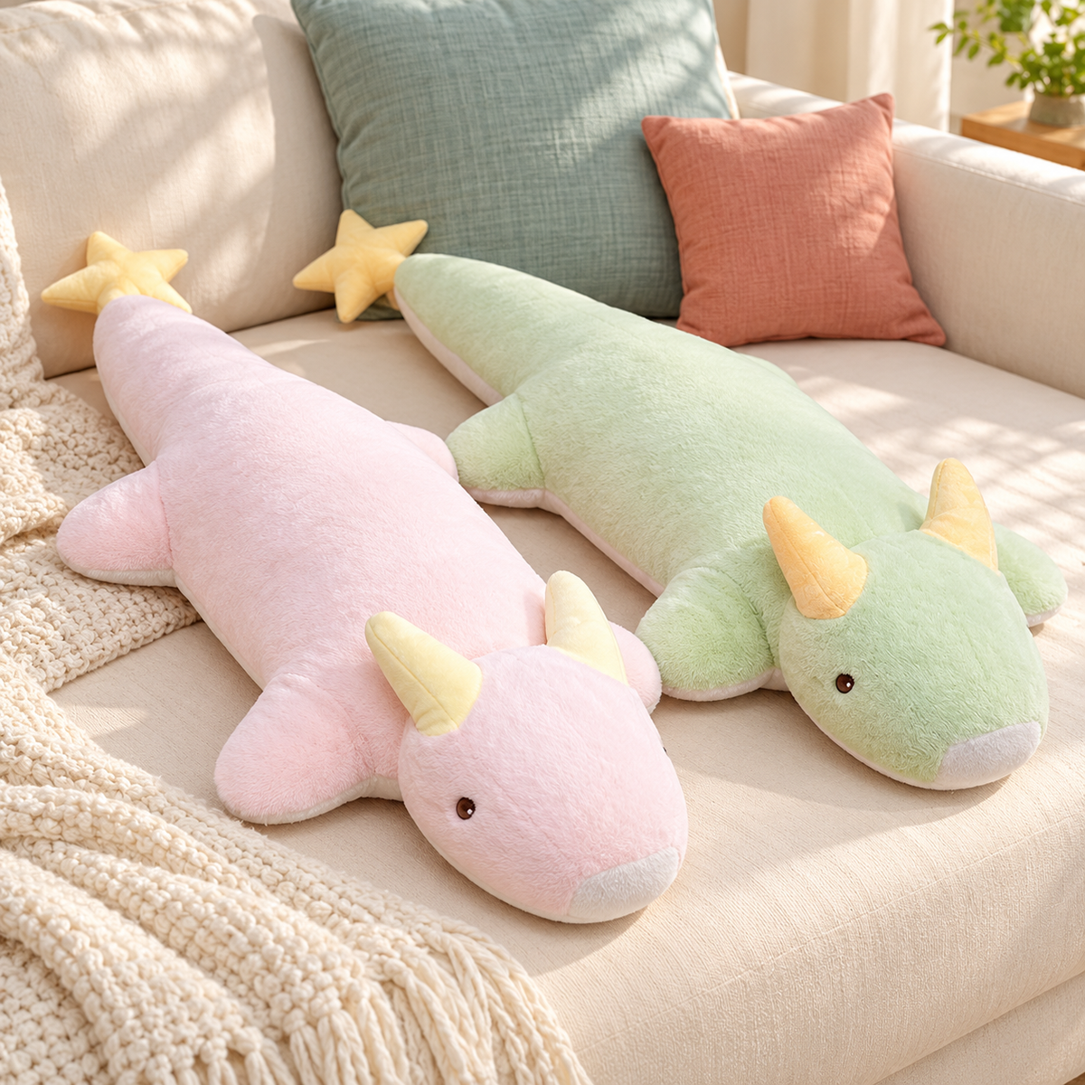 Blush Pink and Mint Green Starry Snooze long dragon plush body pillows with pale yellow horns and star-tipped tails on an ivory sofa