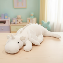 White dragon plush toy on a bed in a child's bedroom with toys and furniture in the background.